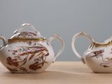 two white and gold teapots sitting on a wooden table