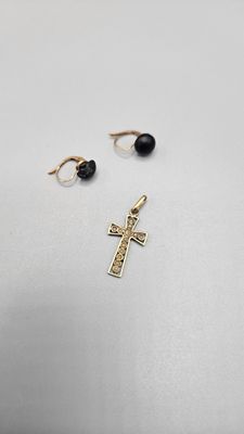 a pair of earrings and a cross on a white surface