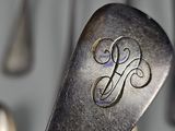 a spoon with a monogram on it in front of a bunch of spoons