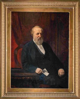 portrait d'un homme en costume noir et chemise blanche, assis sur une chaise