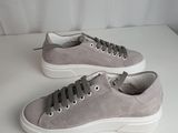 a pair of grey sneakers with white soles on a white surface