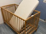 a wooden crib with a mattress on top of it