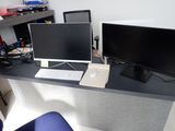 un bureau sur lequel sont posés deux écrans et un ordinateur portable