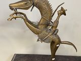 statue en bronze représentant un cheval avec un cavalier sur le dos, posée sur un socle en bois