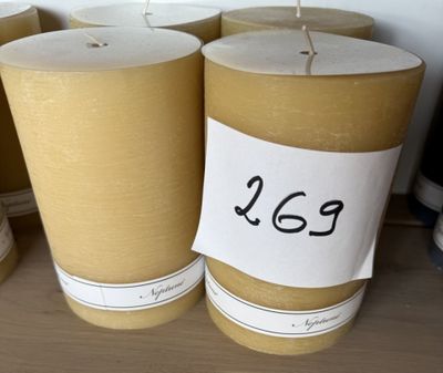 Plusieurs bougies sont alignées sur une table, accompagnées d'une étiquette de prix