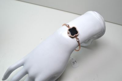 une main de mannequin blanche ornée d'un bracelet noir et doré