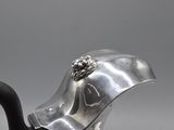 an antique silver teapot with a black handle and a flower on the top