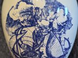 a blue and white vase with a picture of a man on a boat