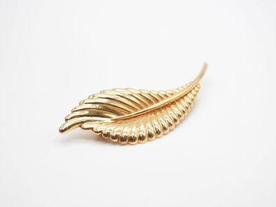 un gros plan d'une broche en feuille d'or sur fond blanc