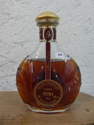 une bouteille de brandy posée sur une table en bois devant un mur blanc
