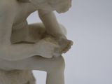 a small statue of a man sitting on a stool
