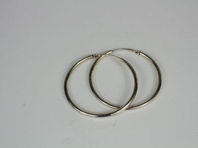 two silver hoop earrings on a white surface
