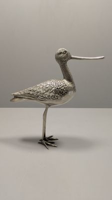 un oiseau en argent au long bec, posé sur une table