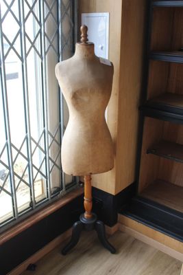 a mannequin on a stand in front of a window