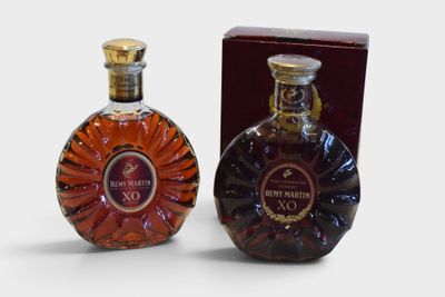 two bottles of brandy sitting next to each other on a white surface