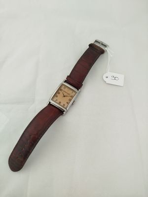 a close up of a watch on a white surface with a tag