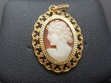 a close up of a gold plated pendant with a woman ' s face