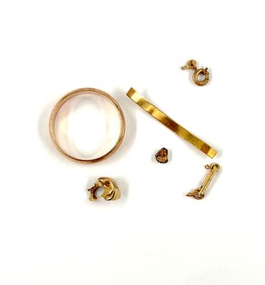 une bague en or et une paire de boucles d'oreilles posées sur une surface blanche