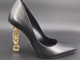 a pair of black high heels with a gold chain on the heel