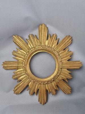 a gold sunburst that is on a white surface