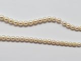 a close up of a pearl necklace on a white surface