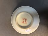 a small white plate with a red design on it