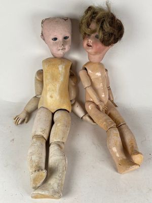 two wooden dolls sitting next to each other on a table