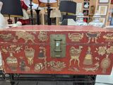a red trunk with gold designs on it sitting on a table