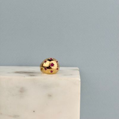 La bague en or repose sur un bloc de marbre blanc.