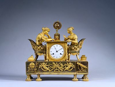 a gold clock with angels on it on a table