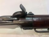 an old gun with a wooden handle on display in a glass case