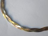 a close up of a gold and silver necklace on a white surface