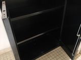 a black cabinet with a door open on a tiled floor