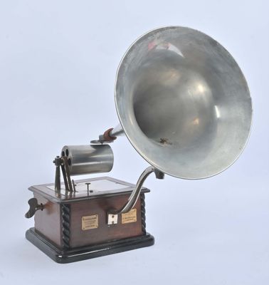 un gramophone argenté posé sur un socle en bois, sur fond blanc