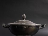 an antique silver plated bowl with a lid on a black background