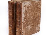 an old book sitting on top of a white surface next to a book