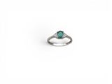 gros plan d'une bague en diamant et émeraude sur fond blanc