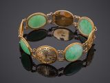 a close up of a bracelet with green stones on a black surface