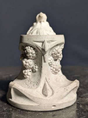 une petite statue représentant une femme avec des grappes de raisin sur la tête