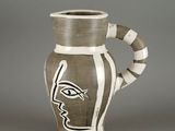 a brown and white vase with a face painted on it