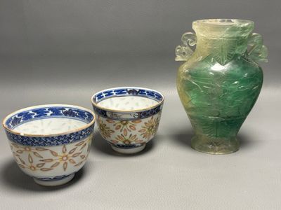 trois tasses posées à côté d'un vase sur une table