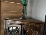 a green parrot sitting on top of a wooden cabinet