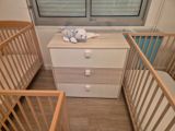 two cribs and a dresser in a small room