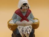 une figurine de femme assise sur une chaise
