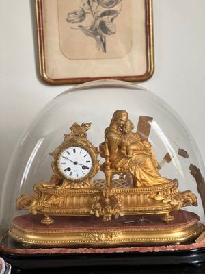 une horloge en or sous un dôme de verre sur une table