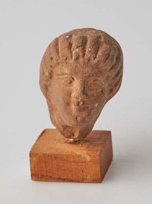 statue représentant la tête d'une femme, posée sur un socle en bois
