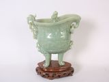 un vase vert posé sur un socle en bois, sur fond blanc