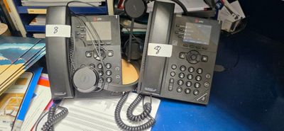two telephones sitting on a desk with a lot of books