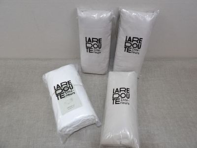 three bags of white towels sitting next to each other on top of a table