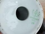 a person holding a white vase with green writing on it